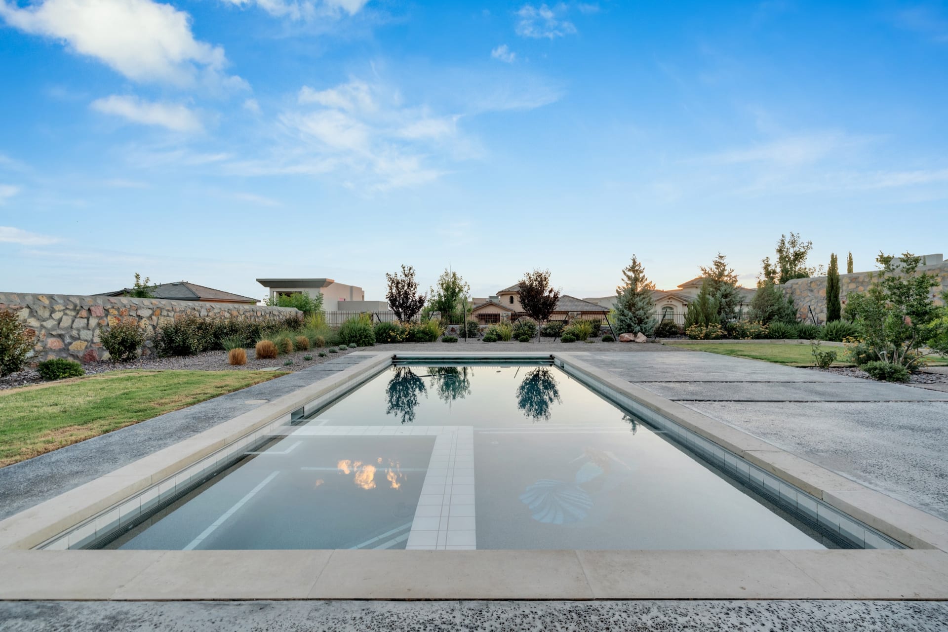 A rectilinear pool at first light, framed by desert planting and an open sky.