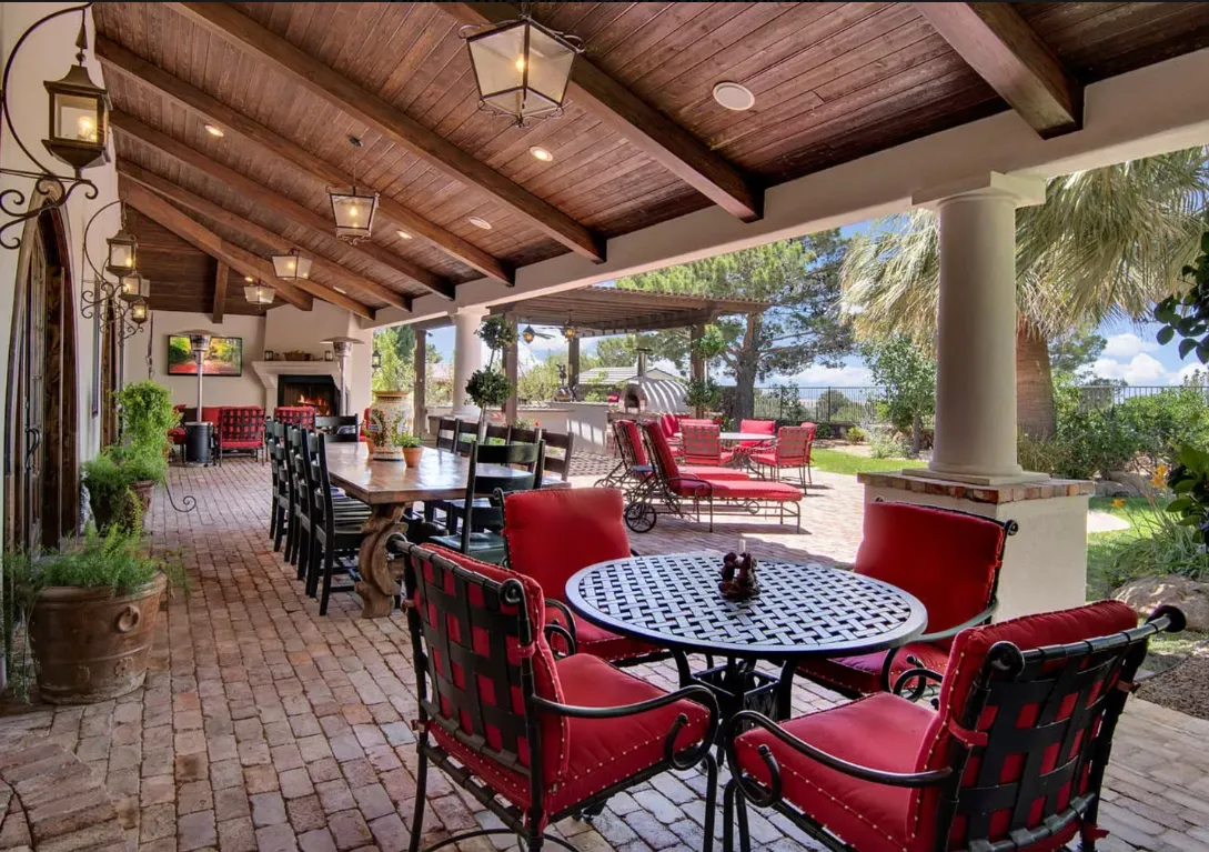 Covered patio with red chairs and tables looking out to a yard.