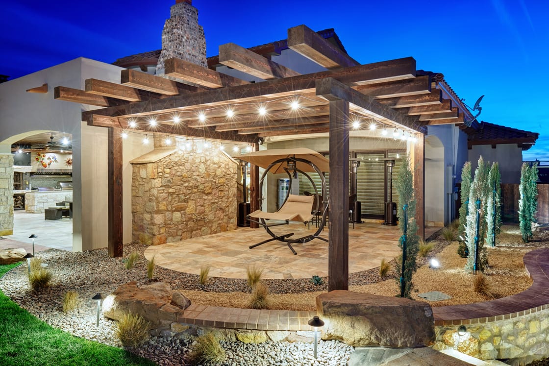 A timber pergola and stone wall illuminated in blue-hour light.