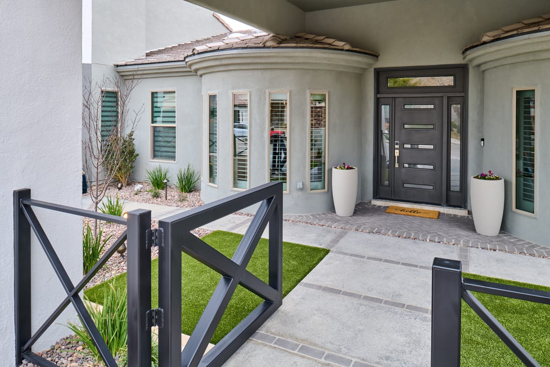 A gray picket gate and planted front garden beside an existing house.